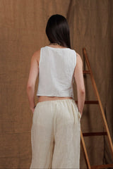 A back view showcasing the relaxed fit of the white muslin vest and beige linen trousers, perfect for warm weather in the UAE and GCC. Made from sustainable, lightweight materials that promote breathability and comfort. Perfect for women seeking natural fabrics that embody elegance and simplicity.