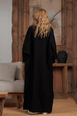 Back view of a long black muslin shirt, showcasing its relaxed fit and soft, textured fabric. The perfect layering piece for summer days in the UAE and GCC region, offering comfort and style.