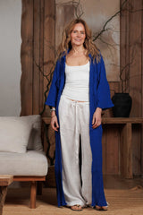 Model wearing a long muslin shirt in vibrant electric blue over white linen pants. The relaxed fit and soft texture of the muslin fabric are perfect for casual summer days in the GCC region, providing lightweight comfort and breathability.