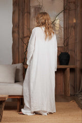 Back view of a long white linen kimono, showcasing its fluid drape and lightweight fabric. Designed for summer styling in Dubai, UAE, and GCC, this piece is perfect for layering over beachwear or city outfits. Photographed in a minimalist, nature-inspired setting, highlighting sustainable fashion.