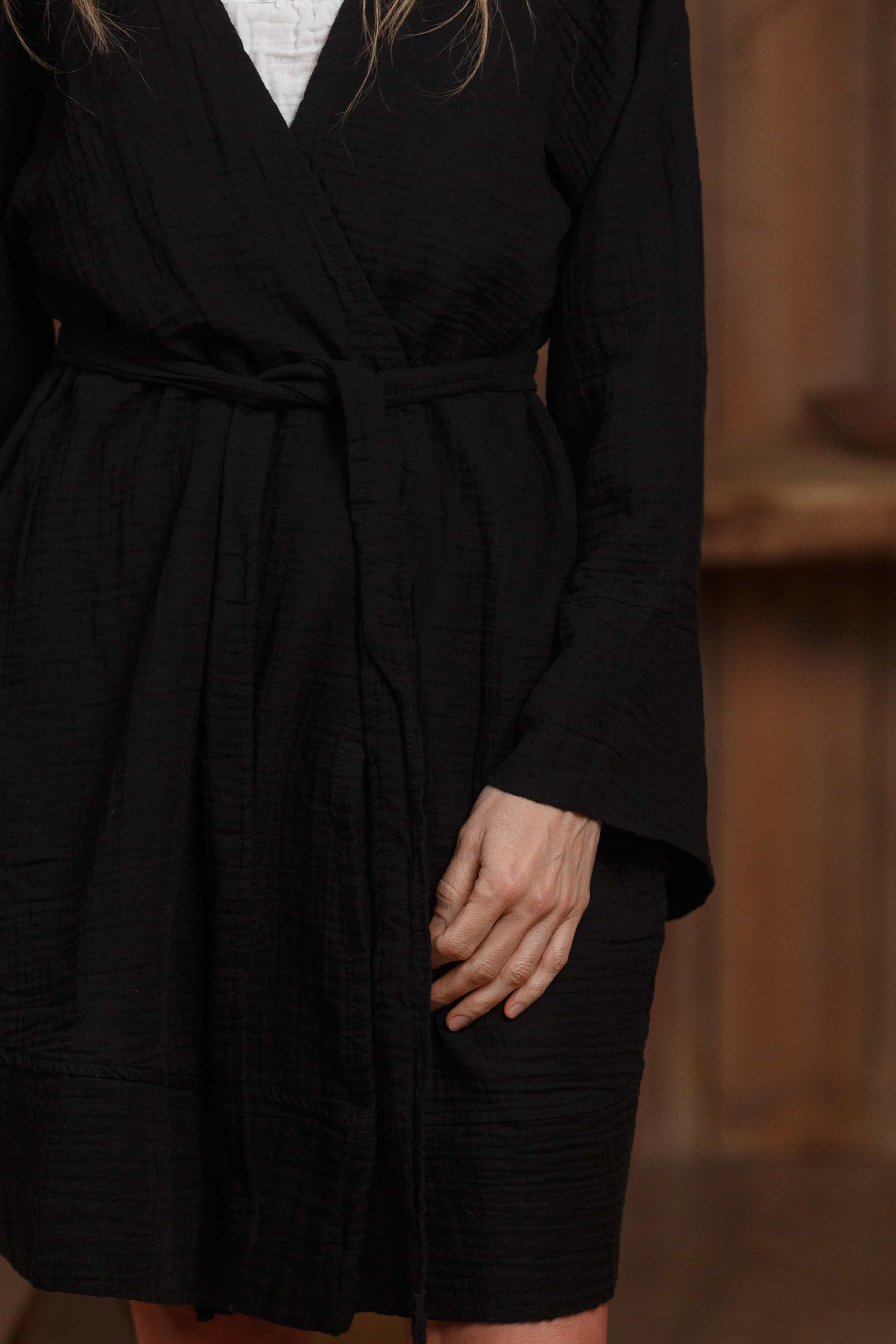 Detailed view of the short black muslin robe, showcasing the textured fabric and minimalist wrap-around belt. Perfect for layering over beachwear or casual outfits in Dubai, UAE, and GCC. Breathable and lightweight for maximum comfort in hot climates.