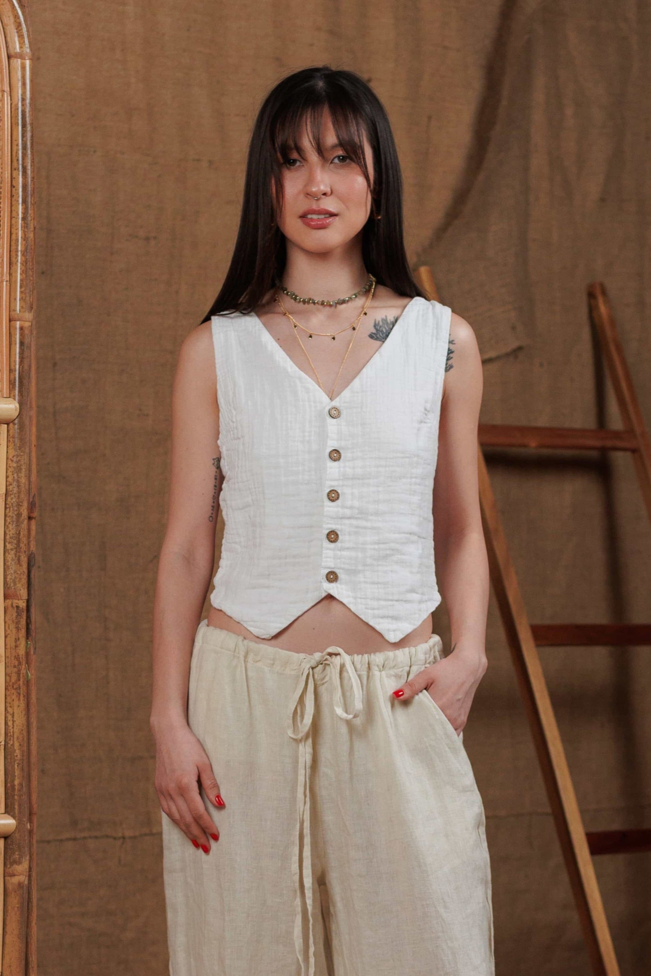 A minimalist white muslin vest paired with breathable beige linen trousers, designed for effortless elegance in hot climates. Ideal for summer days in Dubai, Abu Dhabi, and across the GCC region. Crafted from 100% natural fabrics for maximum comfort and style. Perfect for beach walks, city strolls, or lounging at home.