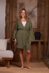 Front view of an olive green short muslin robe with a wrap-around belt, showcasing its lightweight, breathable texture. Perfect for beach cover-ups, resort wear, and city styling in Dubai, UAE, and GCC. Photographed in a minimalist setting that reflects Middle Eastern elegance and sustainable fashion.