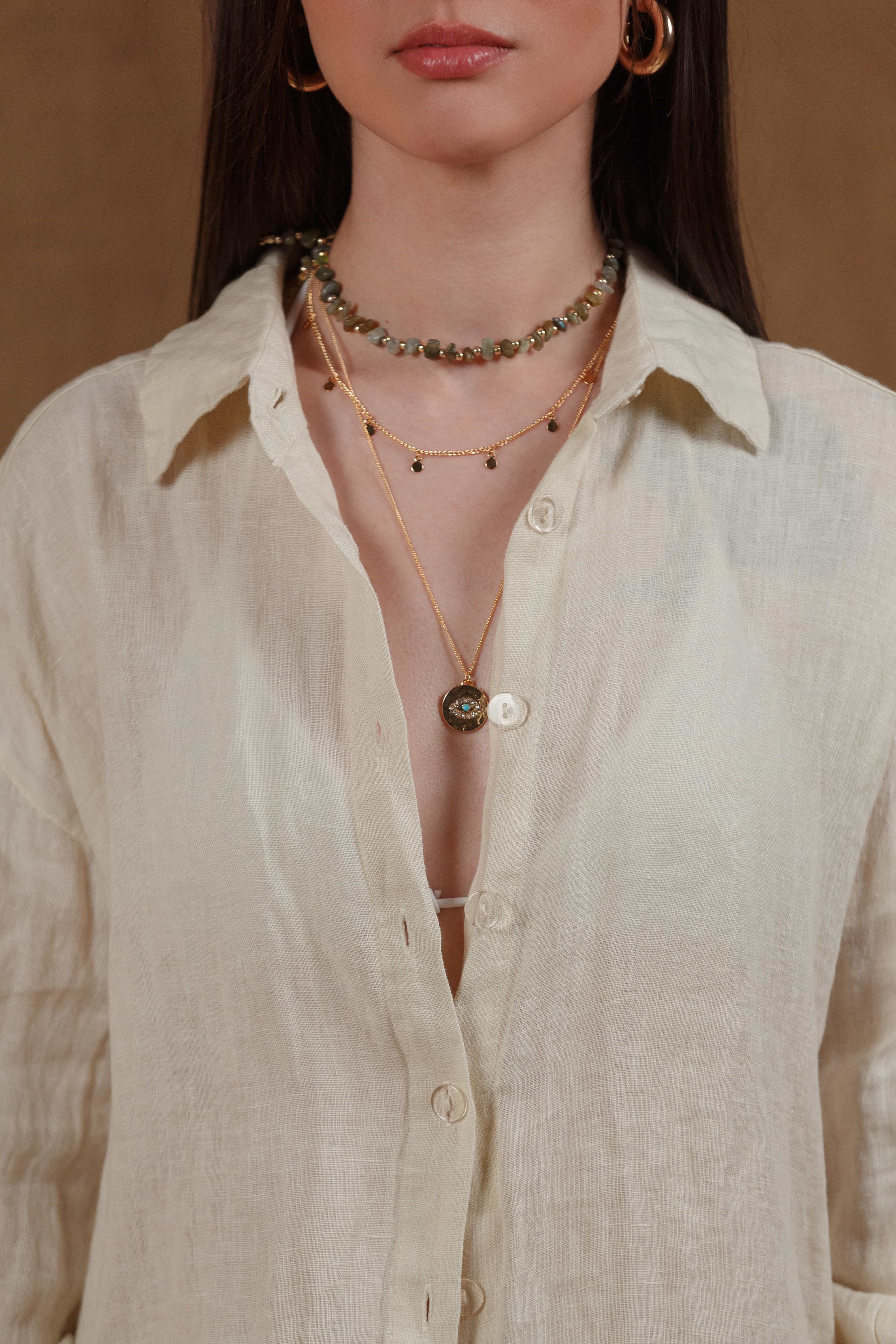 Close-up of the beige linen shirt's button-down front, showcasing its minimalist design and natural linen texture. Perfectly styled with layered jewelry for a chic yet relaxed look, ideal for resort wear and coastal living in the GCC region.