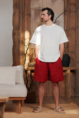 men's white T-shirt paired with red burgundy linen shorts, ideal for the hot summer days of Dubai, UAE, and GCC. Breathable linen fabric ensures comfort and style for beach and urban wear. Captured in a minimalist, nature-inspired setting with soft natural light.
