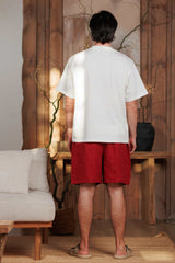 Back view of men's red burgundy linen shorts, designed for summer wear in Dubai, UAE, and GCC. The breathable, lightweight fabric ensures comfort during beach days and city walks. Styled in a minimalist, nature-inspired setting with wooden accents, reflecting sustainable Middle Eastern fashion.